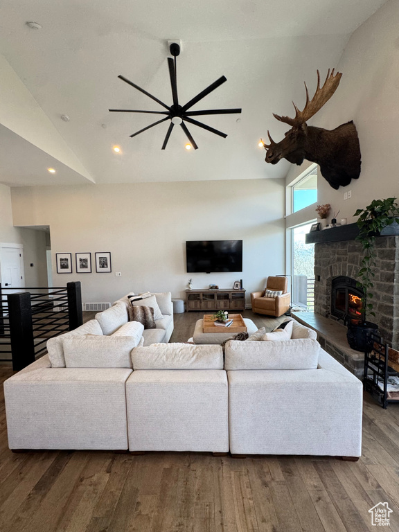Living area with high vaulted ceiling, wood finished floors, a ceiling fan, a fireplace, and recessed lighting