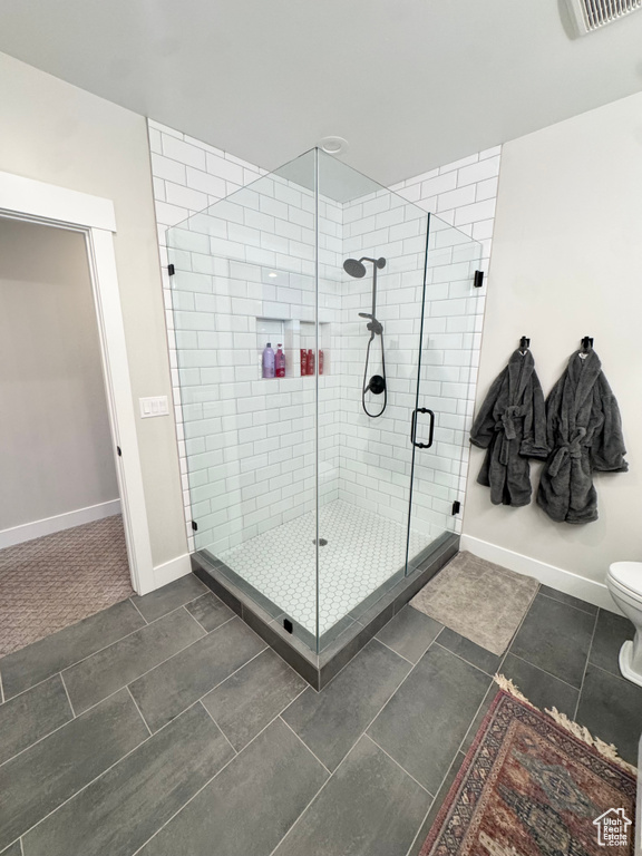 Full bathroom featuring a shower stall, baseboards, tile patterned flooring, and toilet