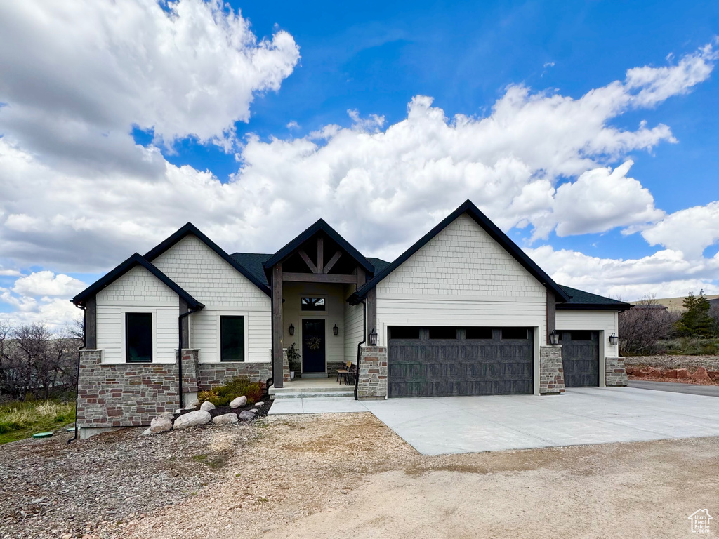 View of front of property featuring stone siding, a garage, and concrete driveway