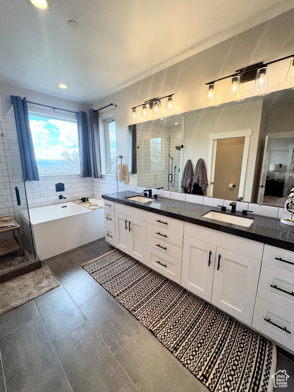 Full bathroom featuring a shower stall, double vanity, a garden tub, backsplash, and recessed lighting