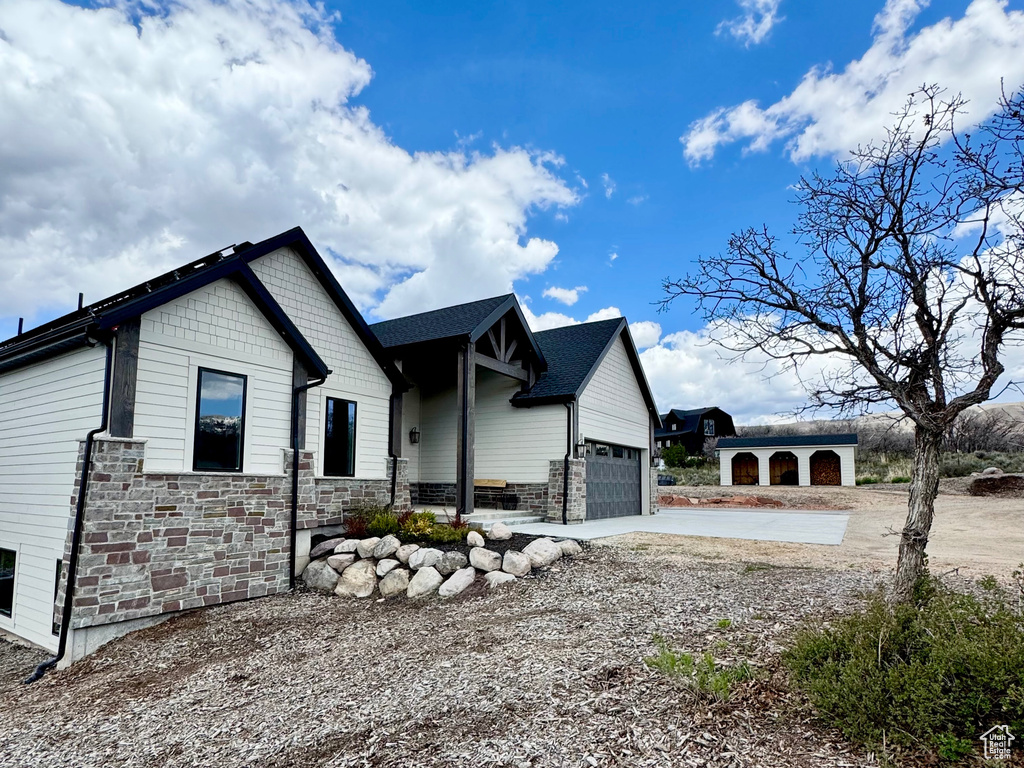 View of side of property with stone siding, concrete driveway, and an attached garage