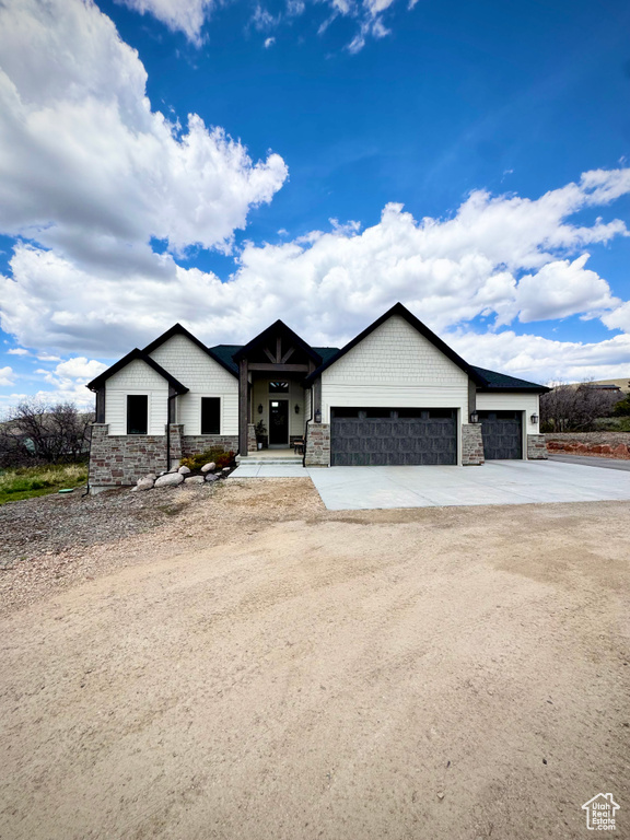 View of front of property featuring stone siding, an attached garage, and driveway