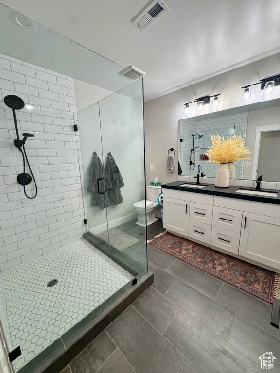 Full bathroom with a shower stall, double vanity, toilet, and tile patterned flooring