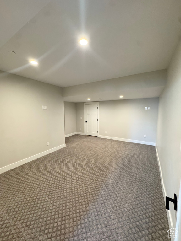 Finished below grade area with dark colored carpet, recessed lighting, and baseboards