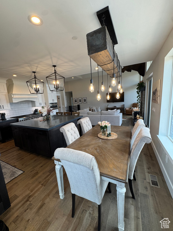 Dining area with a chandelier, dark wood-type flooring, and recessed lighting