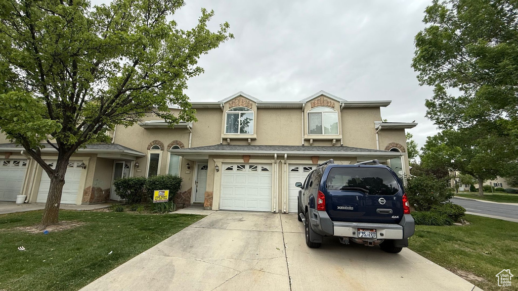 View of front of home featuring stucco siding, driveway, an attached garage, and a front lawn