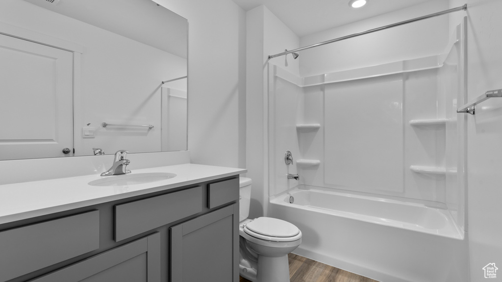 Full bath with toilet, wood finished floors, vanity, and tub / shower combination
