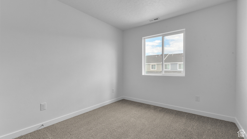 Unfurnished room with carpet, baseboards, and a textured ceiling