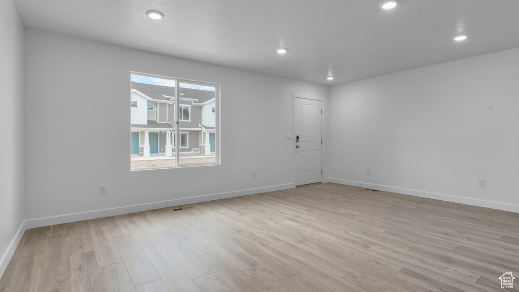 Empty room featuring light wood-style flooring, baseboards, and recessed lighting