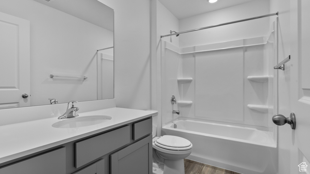 Bathroom with toilet, wood finished floors, vanity, and bathing tub / shower combination