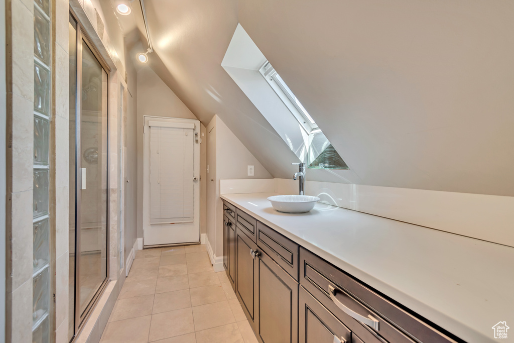 Bar with a skylight, a sink, lofted ceiling, light tile patterned floors, and baseboards