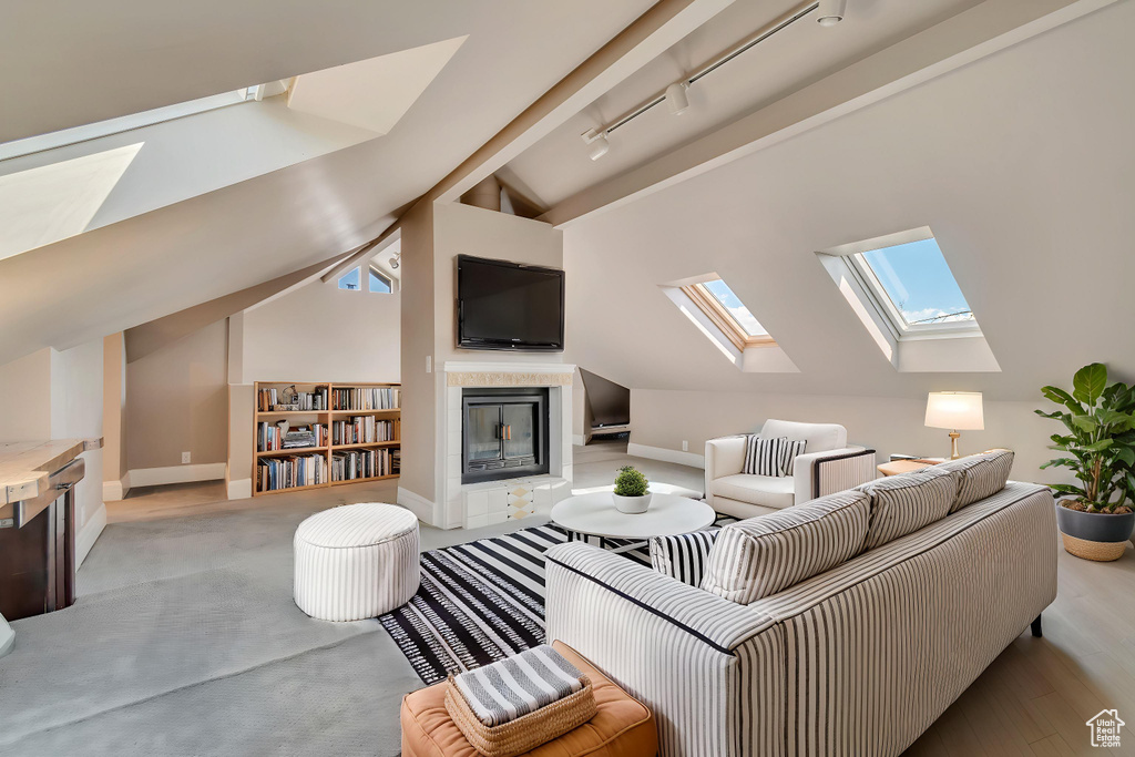 Living area featuring a skylight, a tile fireplace, lofted ceiling, rail lighting, and baseboards