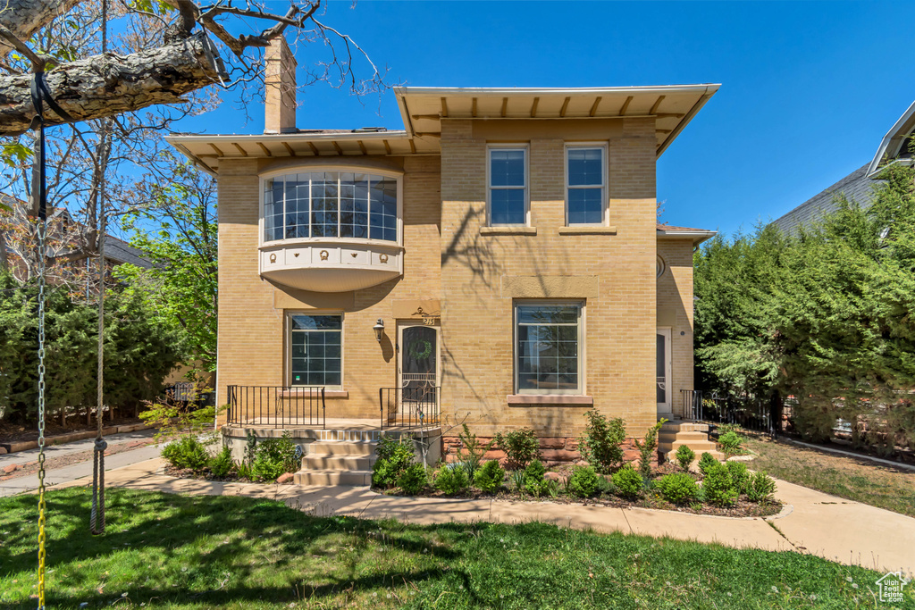 View of front of house featuring a chimney, brick siding, and a front lawn