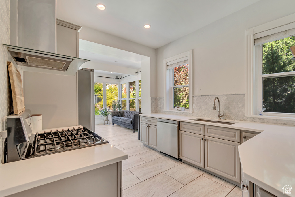 Kitchen featuring stainless steel dishwasher, a sink, light countertops, tasteful backsplash, and recessed lighting