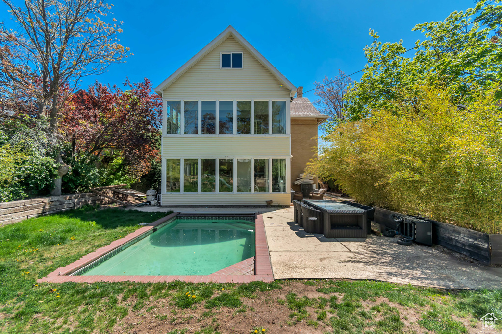 Back of property with a patio, an outdoor pool, and a covered hot tub