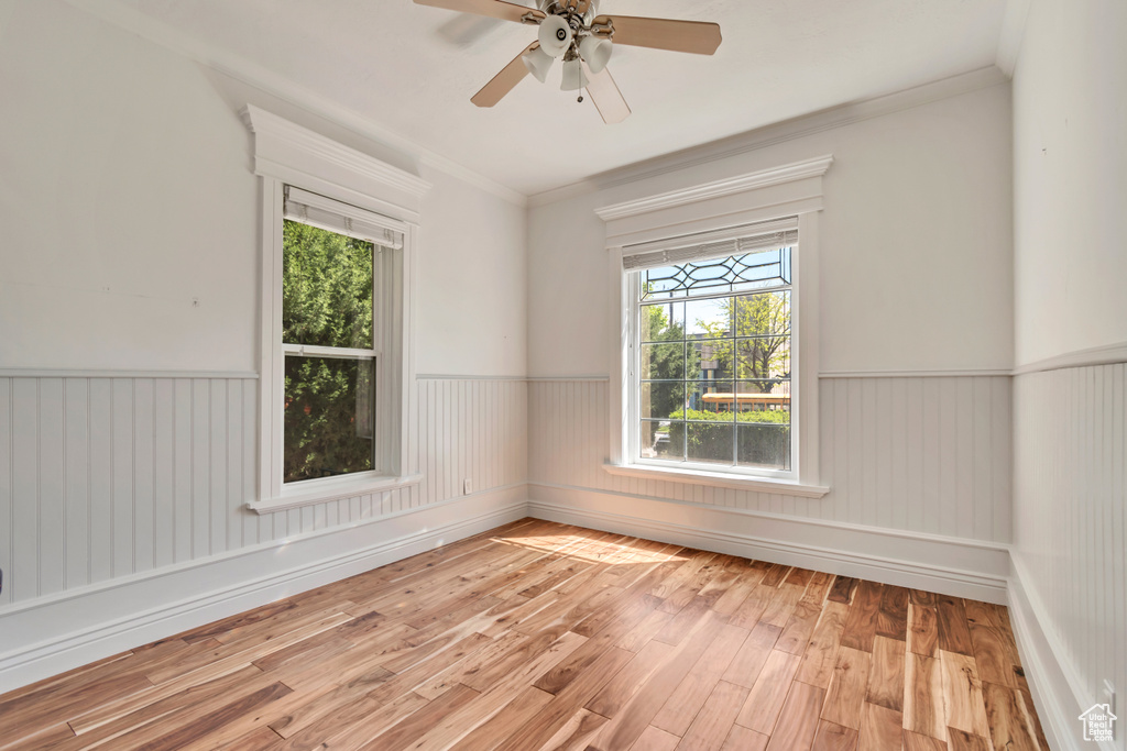 Spare room with hardwood / wood-style floors, wainscoting, crown molding, and ceiling fan
