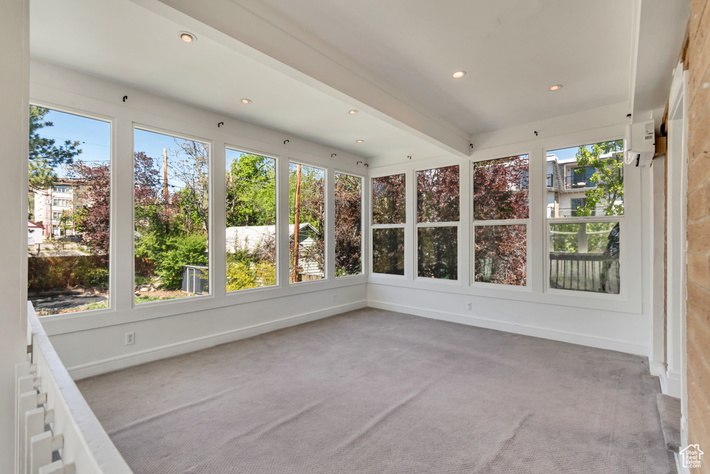 Unfurnished sunroom with plenty of natural light, carpet floors, recessed lighting, baseboards, and beam ceiling