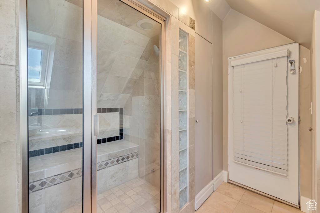 Bathroom featuring a shower stall, tile patterned floors, and vaulted ceiling