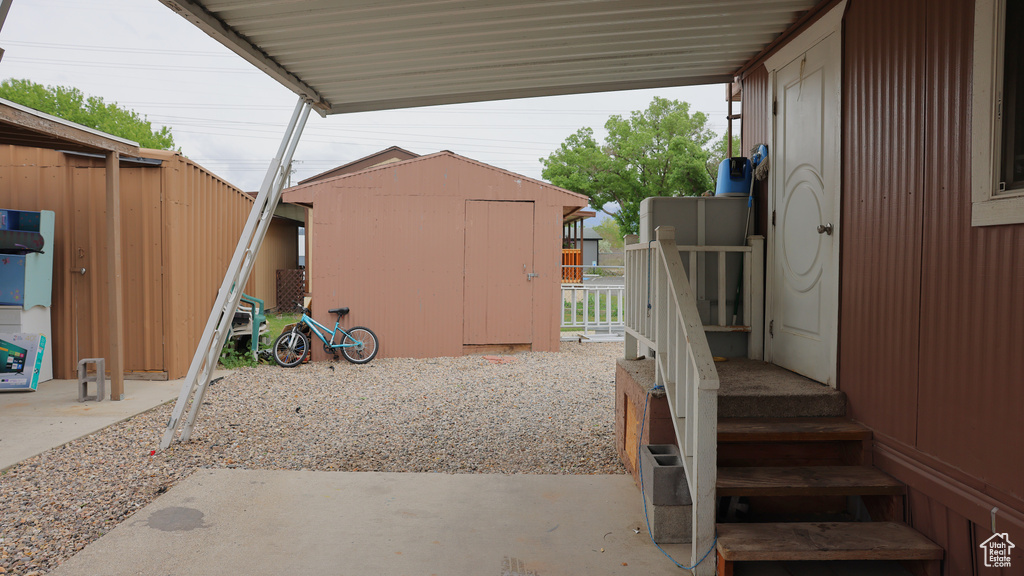 View of patio with a storage unit, an outbuilding, and fence