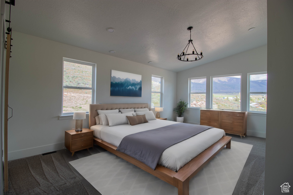 Bedroom with baseboards, light colored carpet, vaulted ceiling, and a textured ceiling