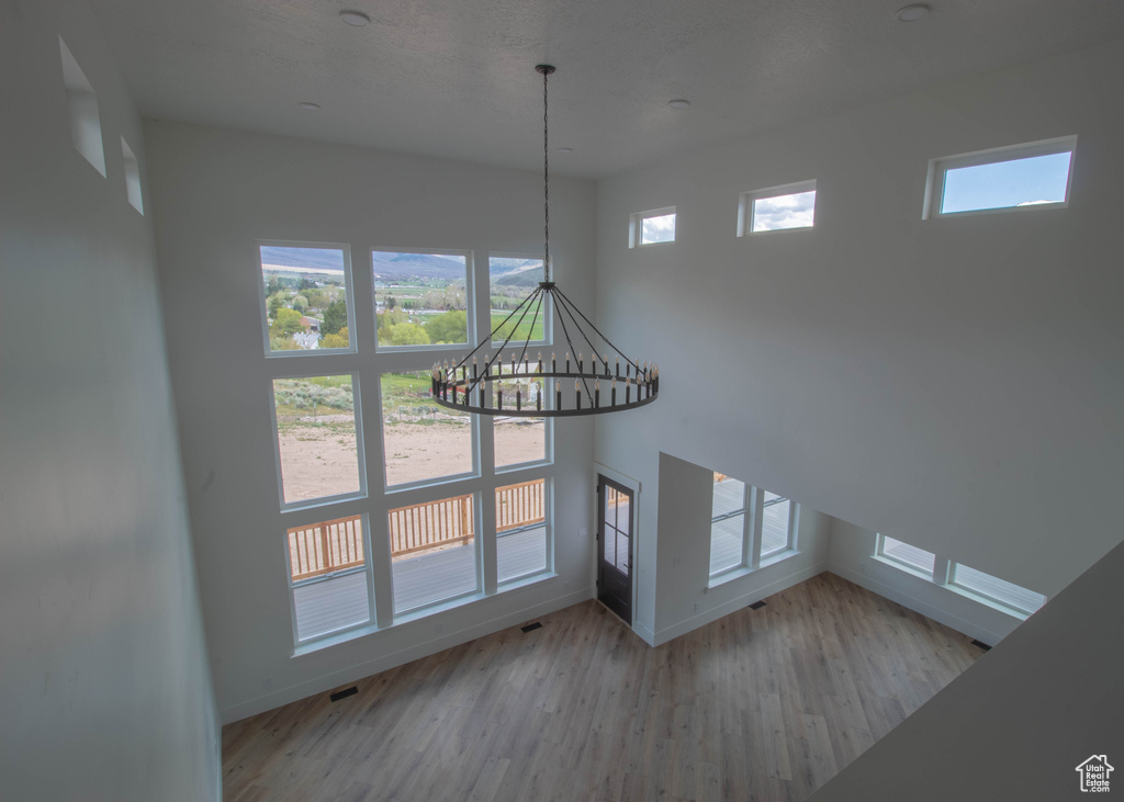 Unfurnished living room featuring baseboards, a chandelier, and wood finished floors