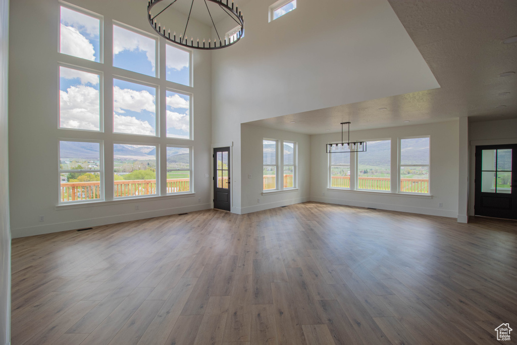 Unfurnished living room with a chandelier, baseboards, and wood finished floors
