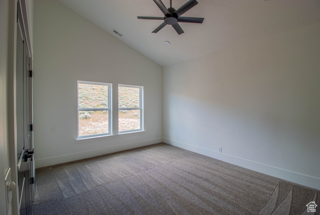 Empty room featuring baseboards, dark carpet, ceiling fan, and high vaulted ceiling