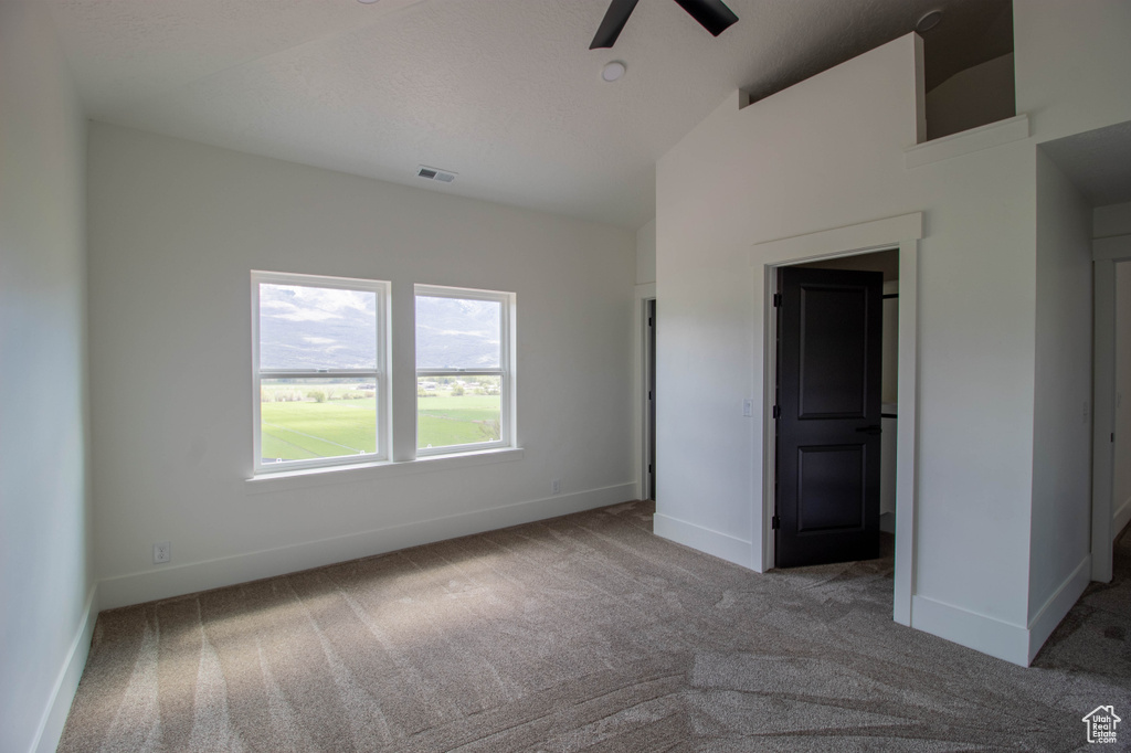 Unfurnished bedroom featuring carpet floors, baseboards, a ceiling fan, and high vaulted ceiling