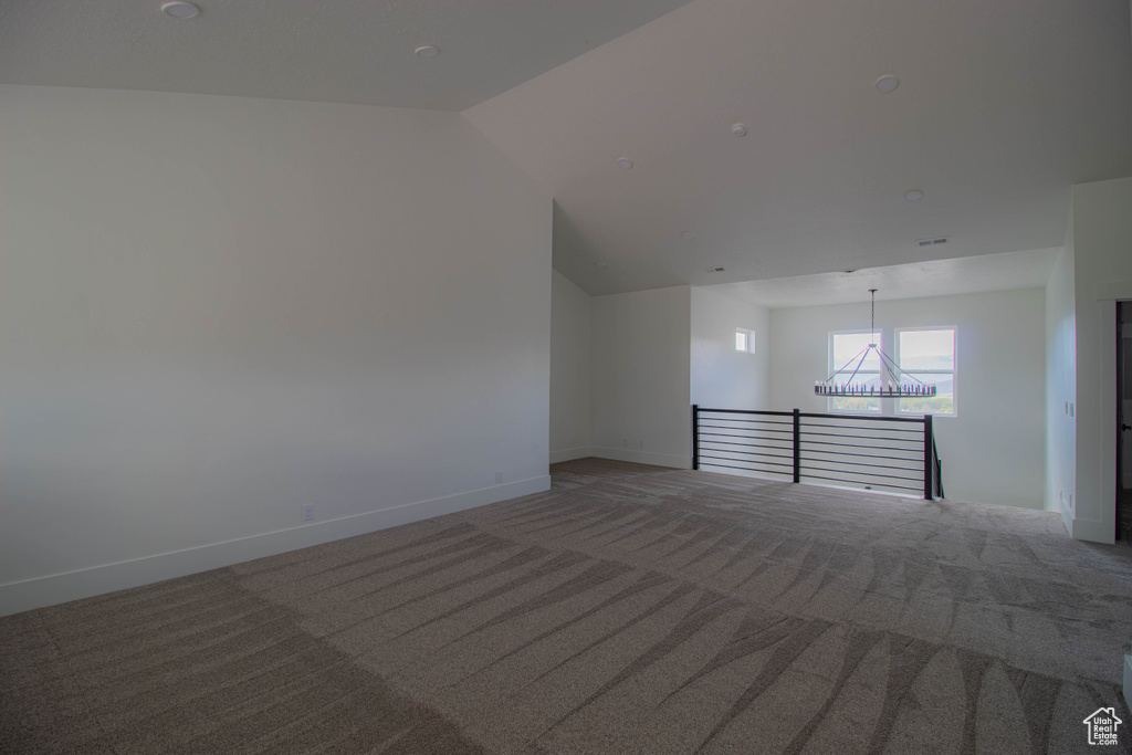 Unfurnished room with light colored carpet, a chandelier, baseboards, and vaulted ceiling