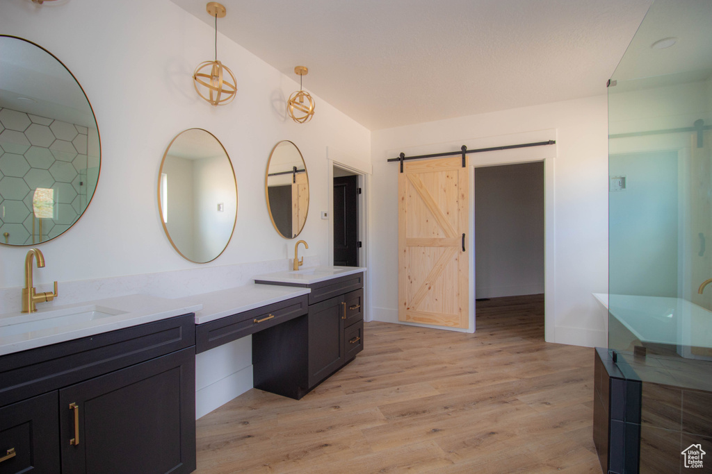 Bathroom featuring wood finished floors, double vanity, and baseboards