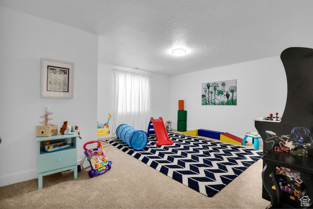 Rec room featuring carpet flooring, a textured ceiling, and baseboards
