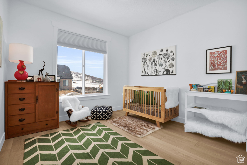 Bedroom featuring wood finished floors, a crib, a mountain view, and baseboards