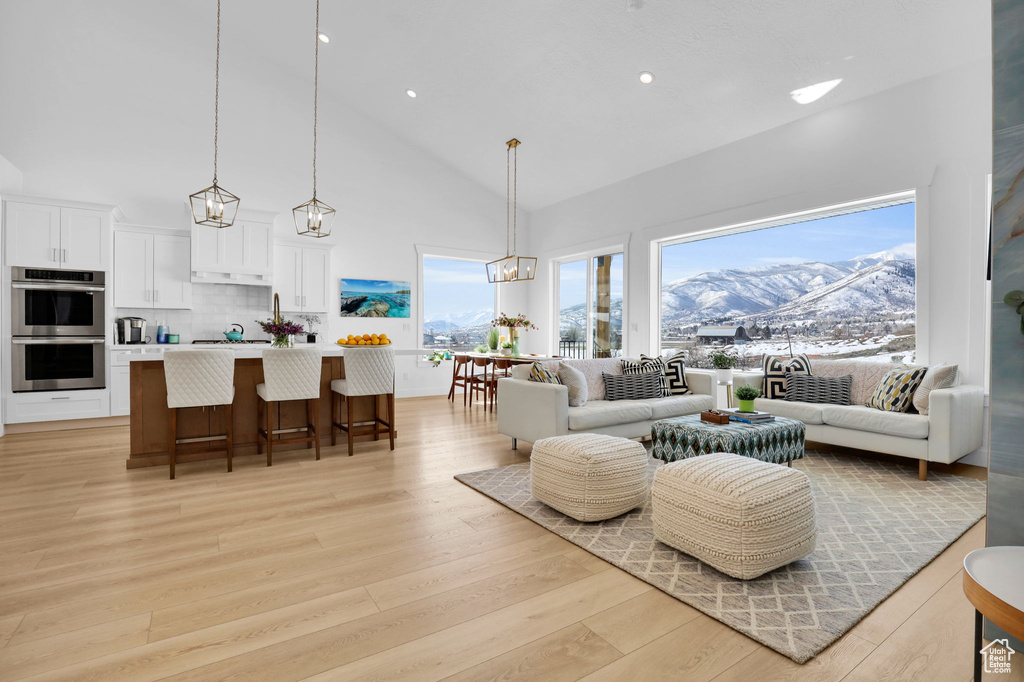 Living area with high vaulted ceiling, light wood finished floors, a chandelier, recessed lighting, and a mountain view