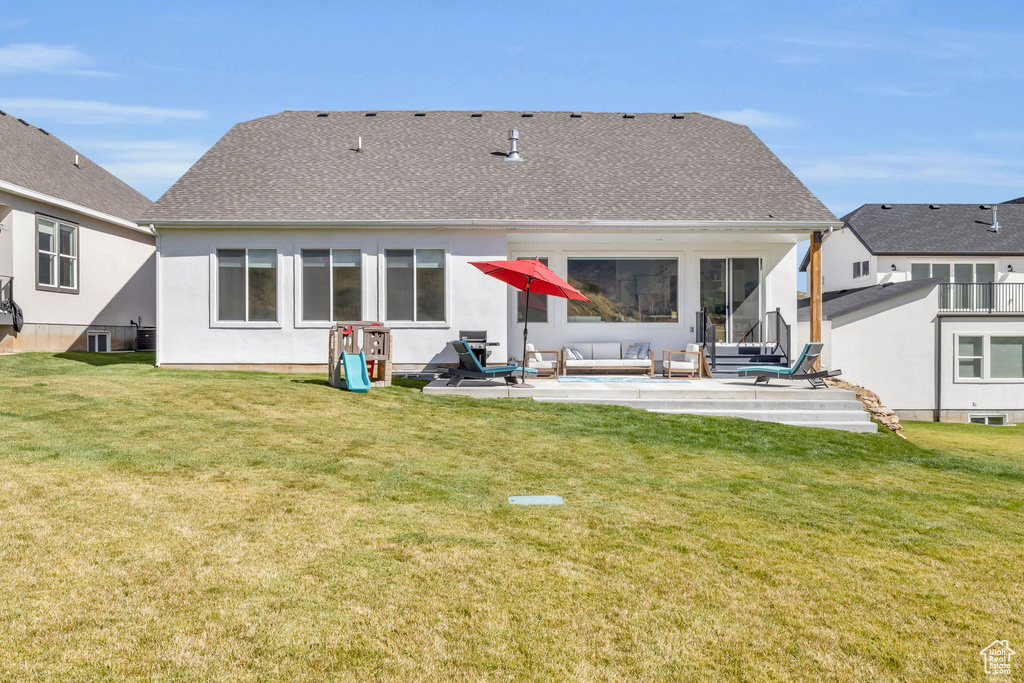 Back of property with outdoor lounge area, a patio, a lawn, and a shingled roof