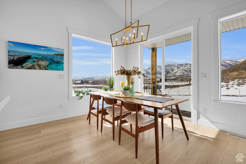 Dining room with a mountain view, light wood-type flooring, a chandelier, and baseboards