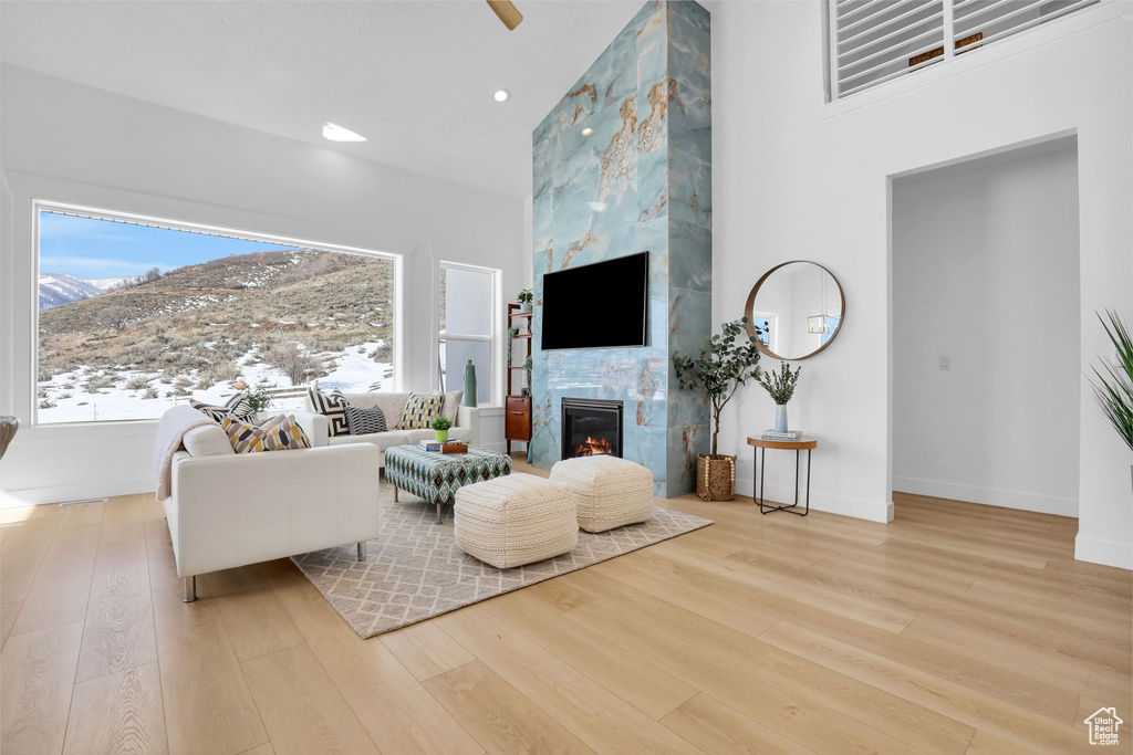 Living room with wood finished floors, a mountain view, a tile fireplace, baseboards, and recessed lighting