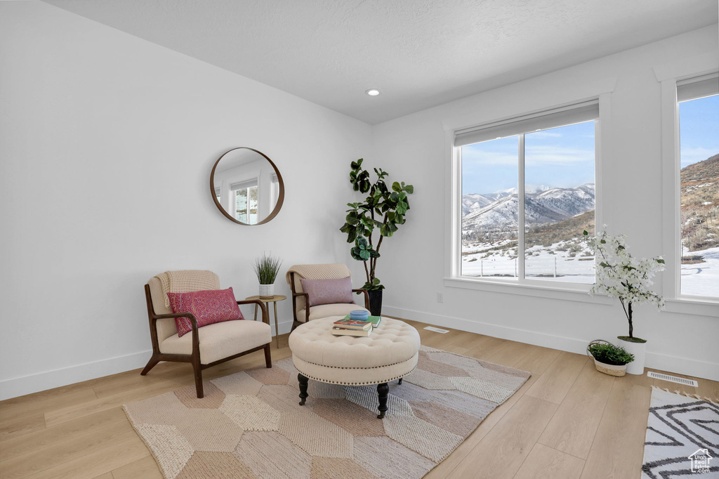 Sitting room with a mountain view, plenty of natural light, light wood-style flooring, and recessed lighting