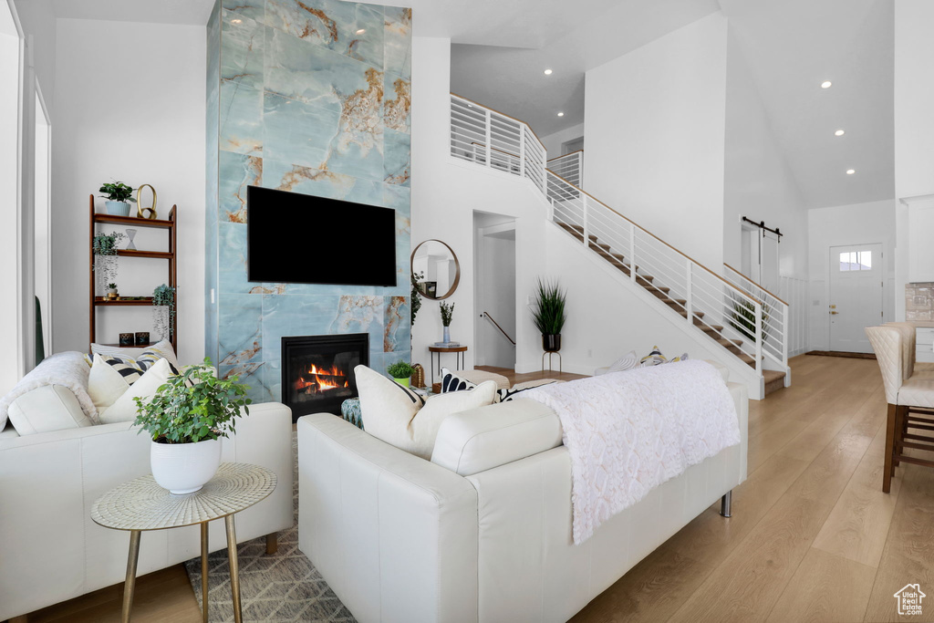 Living room with light wood finished floors, a high end fireplace, recessed lighting, high vaulted ceiling, and stairway