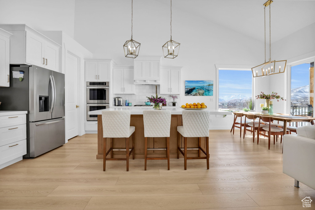 Kitchen featuring appliances with stainless steel finishes, a chandelier, light countertops, backsplash, and white cabinets
