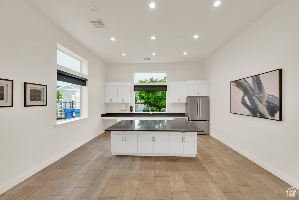 Kitchen featuring freestanding refrigerator, healthy amount of natural light, recessed lighting, dark countertops, and a kitchen island