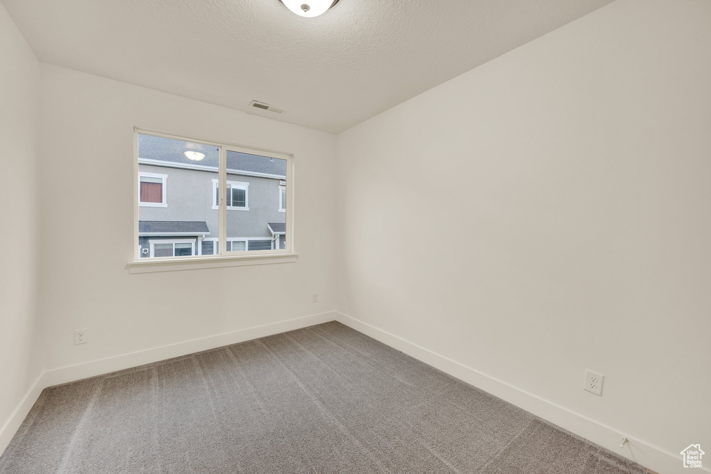 Carpeted spare room with baseboards and a textured ceiling