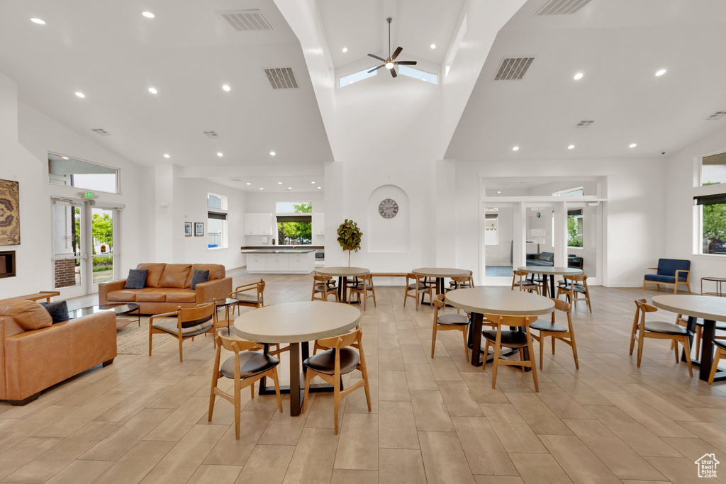 Dining area featuring high vaulted ceiling, ceiling fan, light wood-style flooring, and recessed lighting