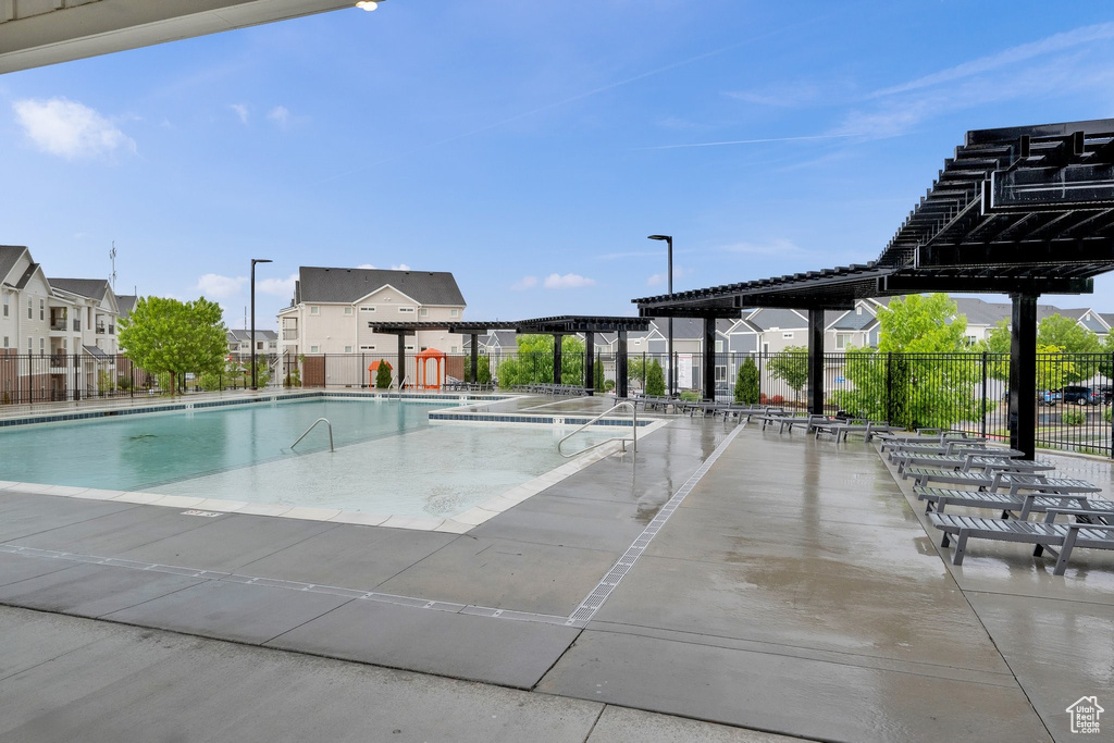 Community pool featuring a pergola, fence, and a residential view