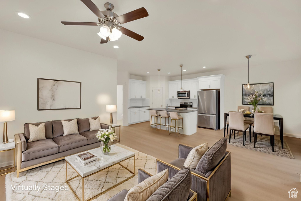 Living room with light wood-type flooring, ceiling fan, recessed lighting, and baseboards