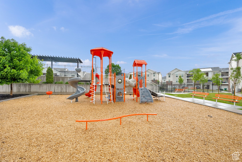 Communal playground featuring fence and a residential view