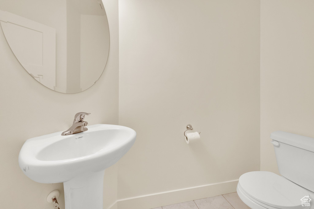 Bathroom with toilet, tile patterned flooring, baseboards, and a sink