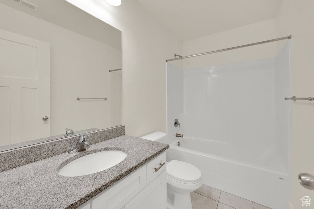Bathroom featuring toilet, tile patterned flooring, vanity, and  shower combination