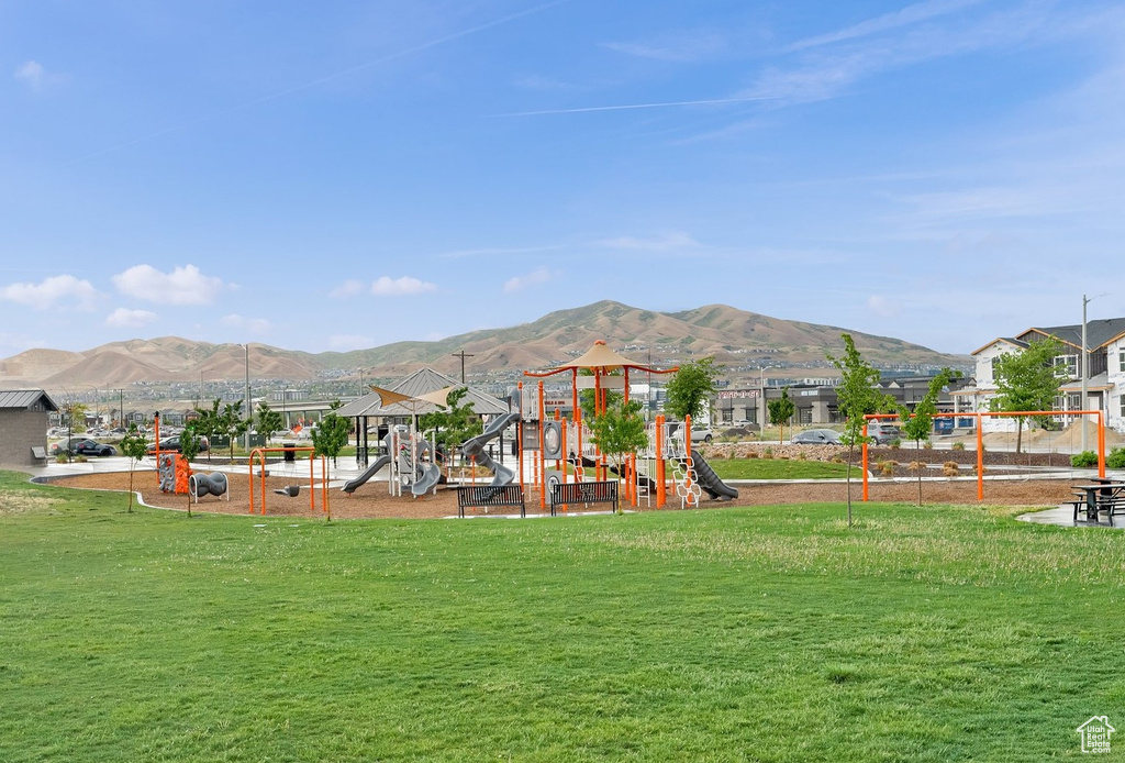 View of grassy yard with a playground and a mountain view