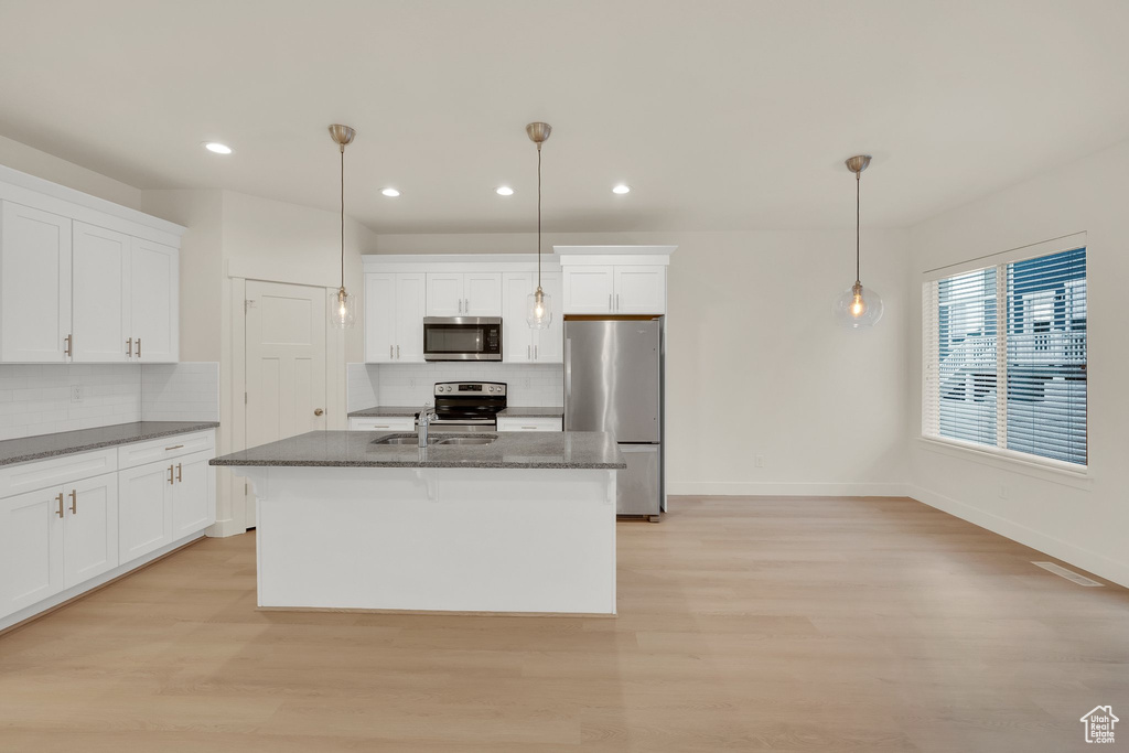 Kitchen featuring appliances with stainless steel finishes, recessed lighting, decorative backsplash, light wood-style floors, and baseboards