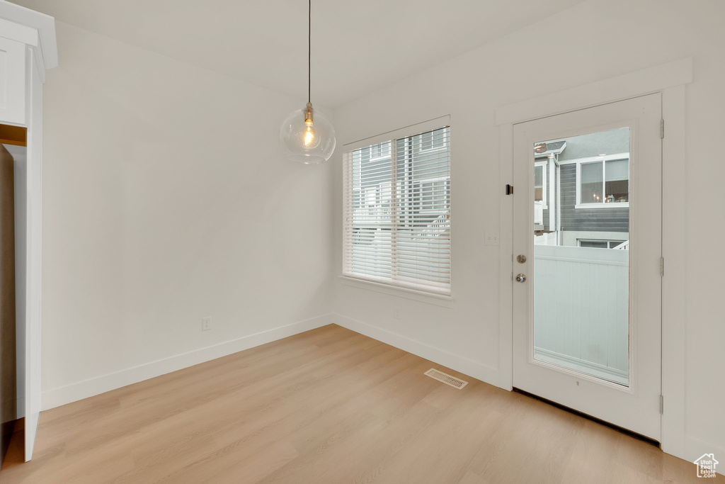 Unfurnished dining area featuring light wood-type flooring and baseboards